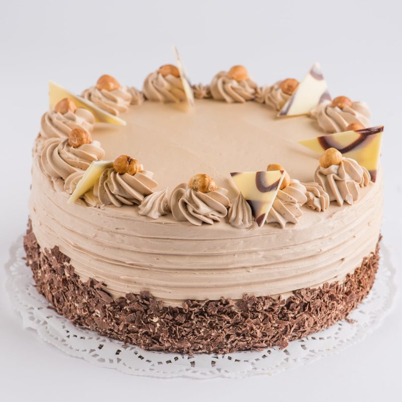 A hazelnut torta finished with piped cream, hazelnuts and chocolate shards